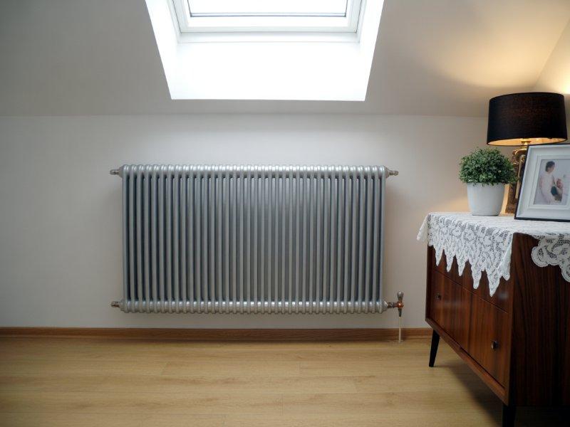 Grzejnik ścienny zamontowany pod oknem w pomieszczeniu mieszkalnym